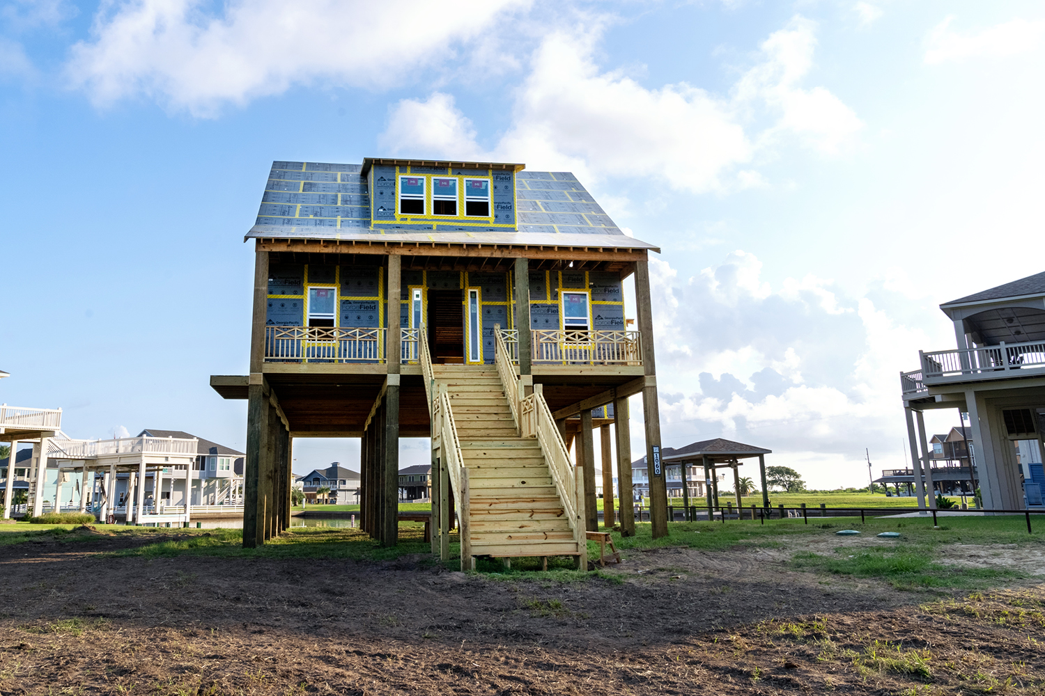 Cape Cod-style home on pilings sheathed in ForceField® Weather Barrier System with visible gold ForceField® Premium Tape.