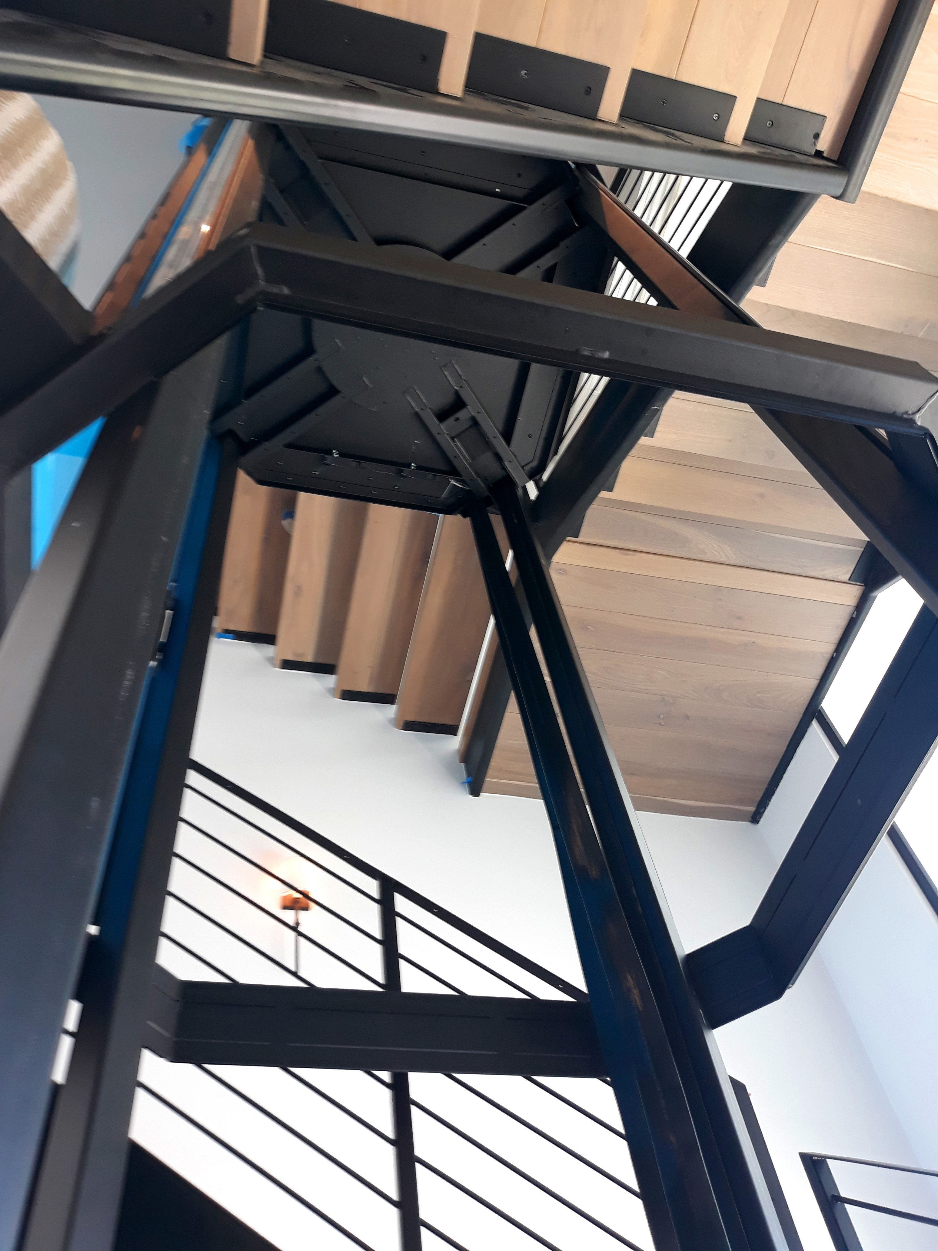 The steel frame of the integrated hoistway being installed within the winding staircase.