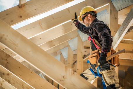 A custom home builder works on the roof of a house