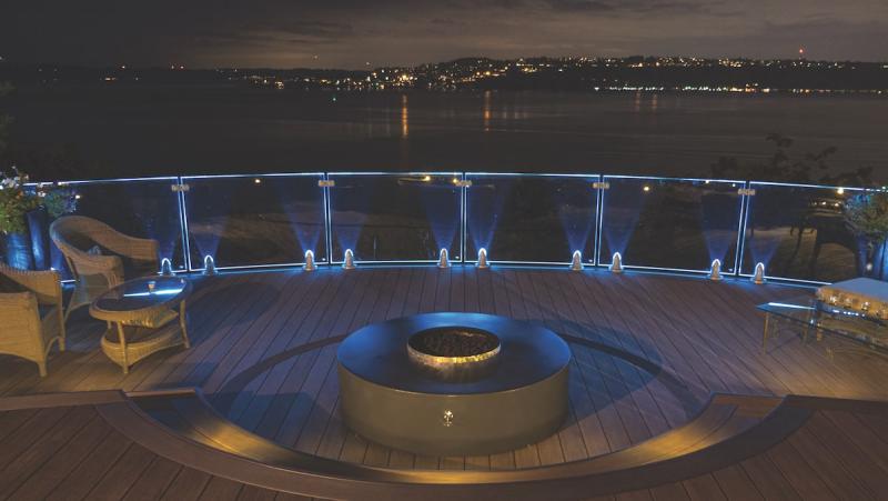 Deck with fire pit feature and night time view of the bay